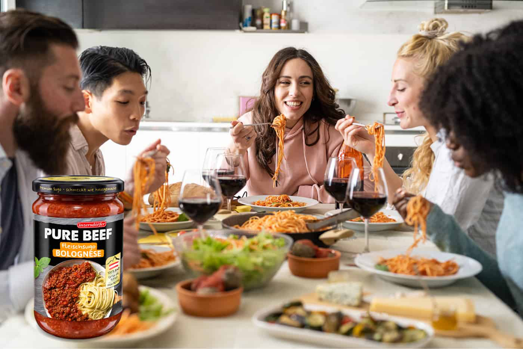 Fünf junge Menschen essen gemeinsam Spaghetti mit Tomatensoße an einem großen Tisch und Sugo Bolognese.